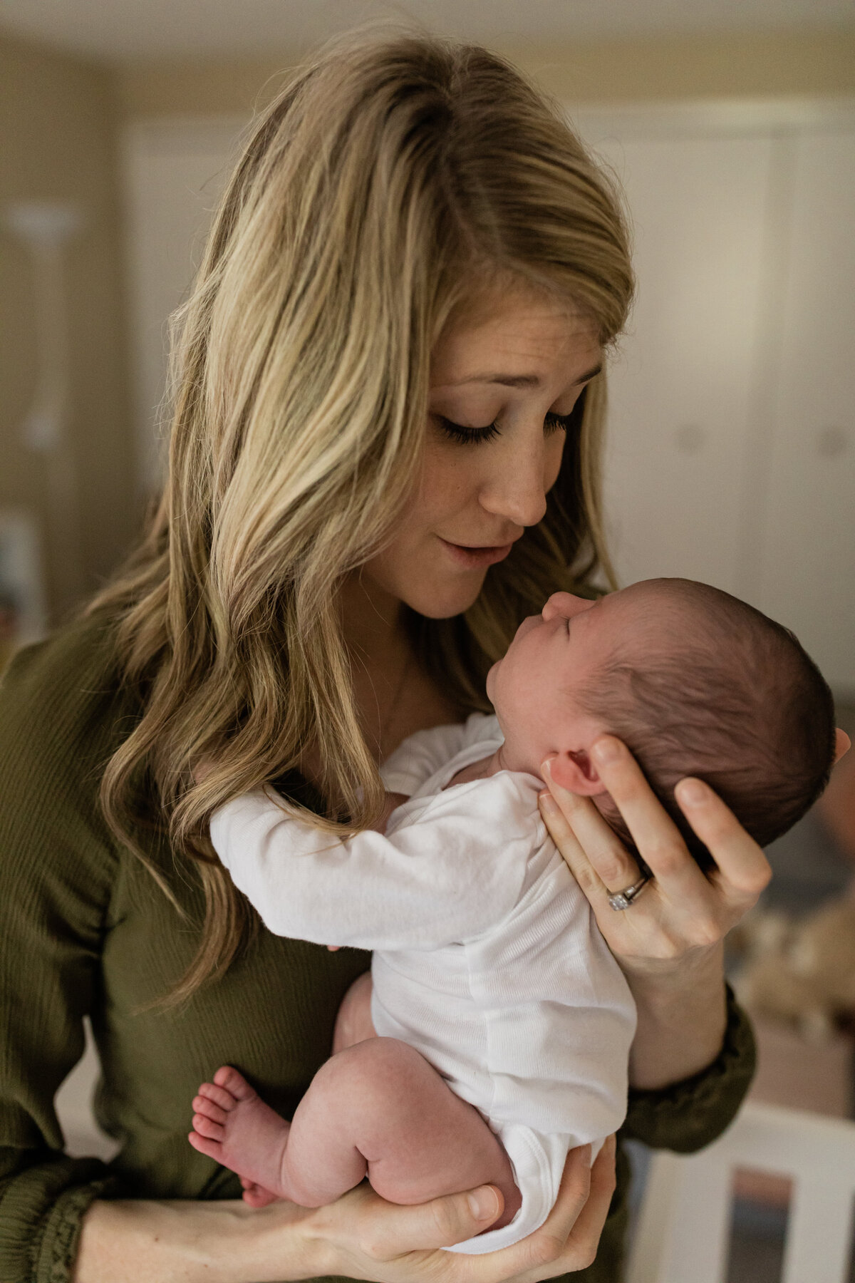 mom holding newborn baby boy in nursery