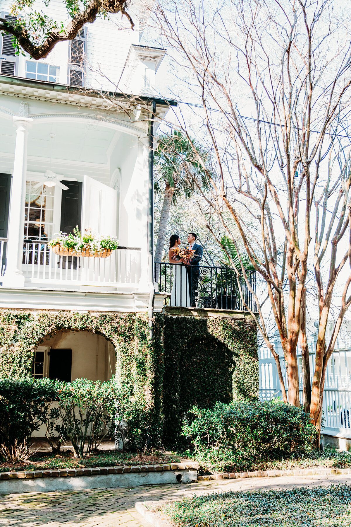 a far away shot of a bride and groom on the porch of their venue