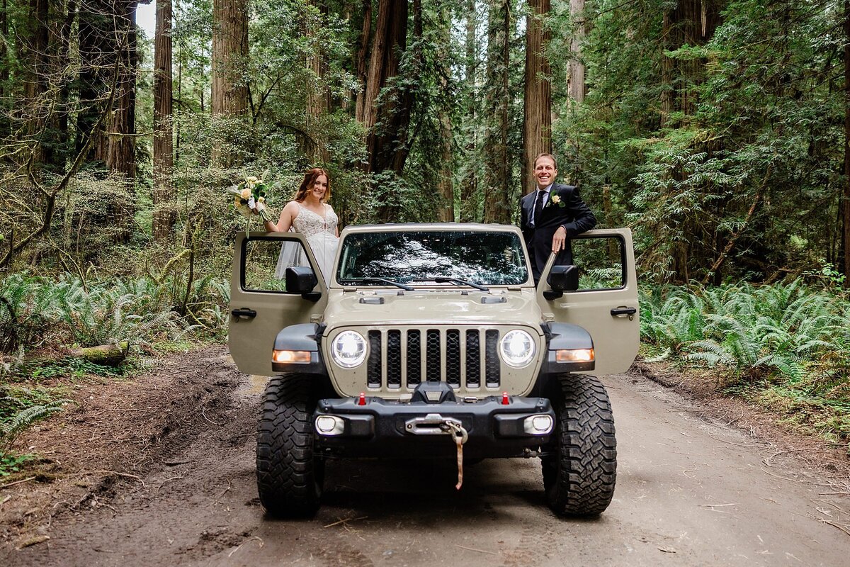 A bride and groom stand on top of their Jeep.