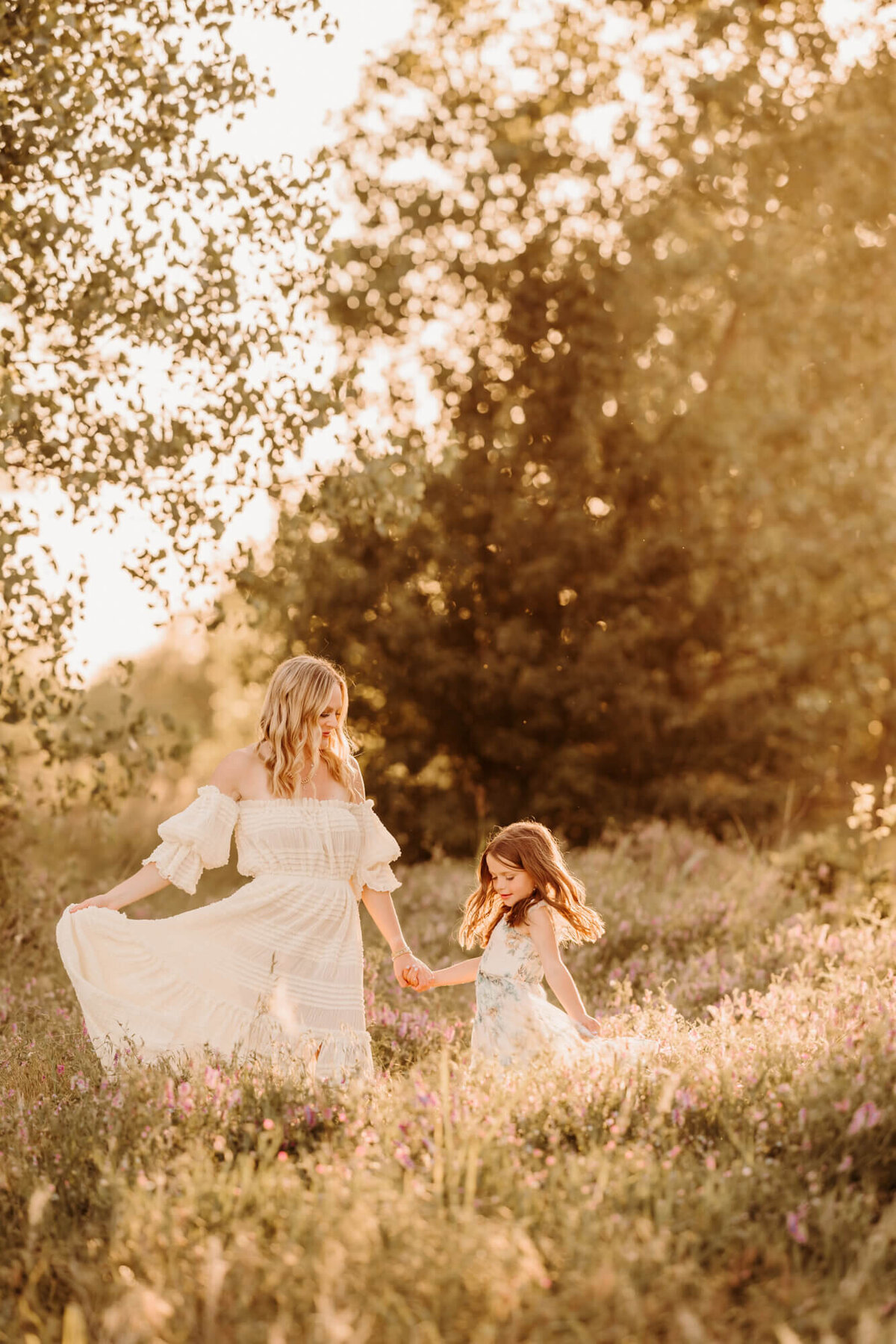 Mother and daughter dance in a field  in Oklahoma City while holding their dresses.