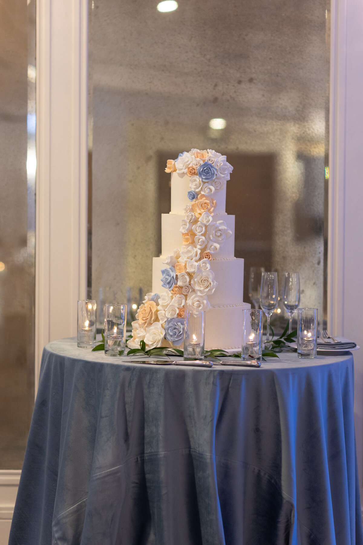 A four tiered wedding cake with flowers down one side