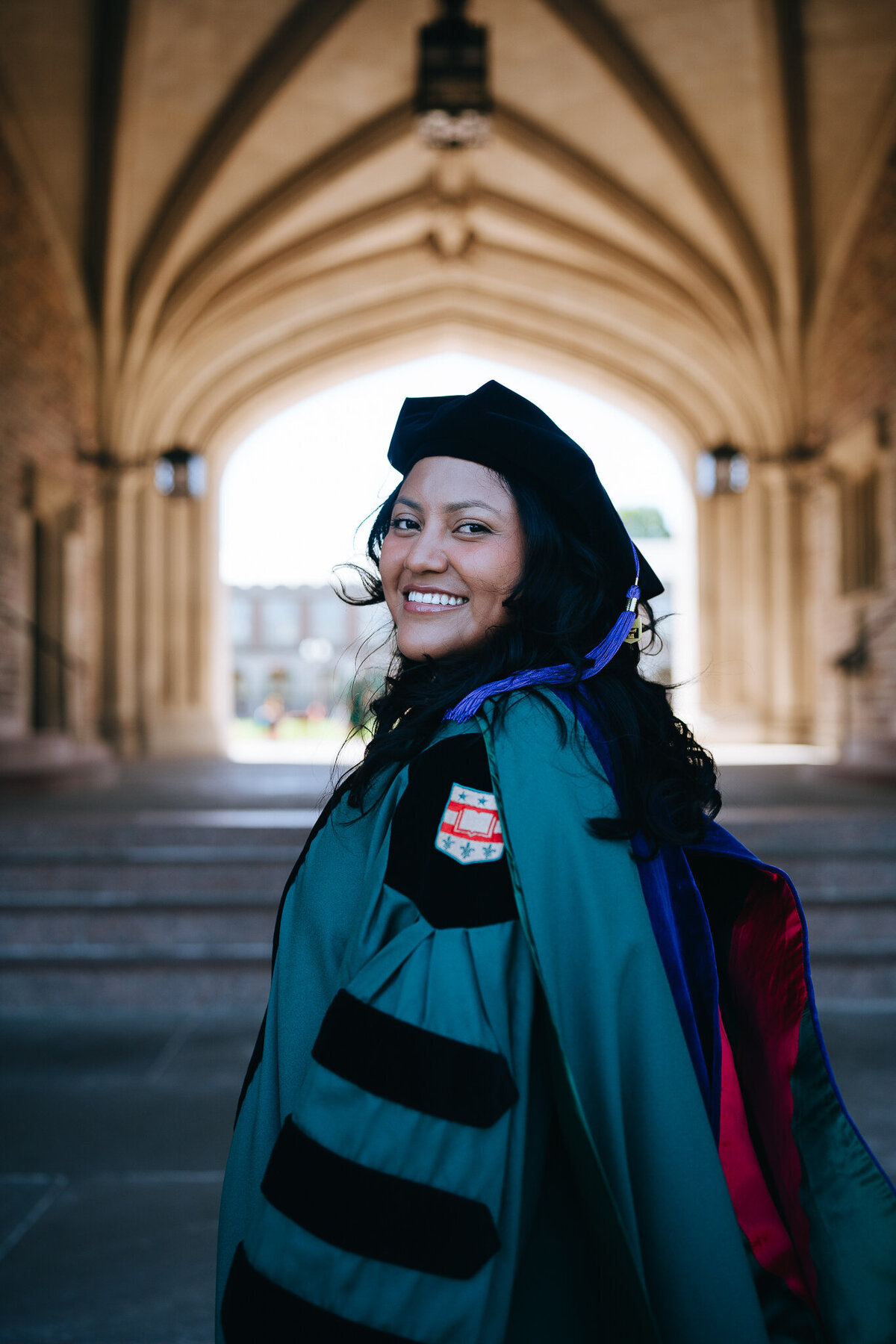 washu law grad wearing regalia standing under brookings hall