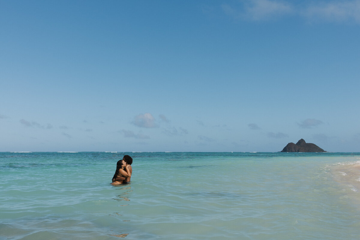 A romantic couple standing in the ocean in Hawaii, an artistic moment of destination elopement photography.