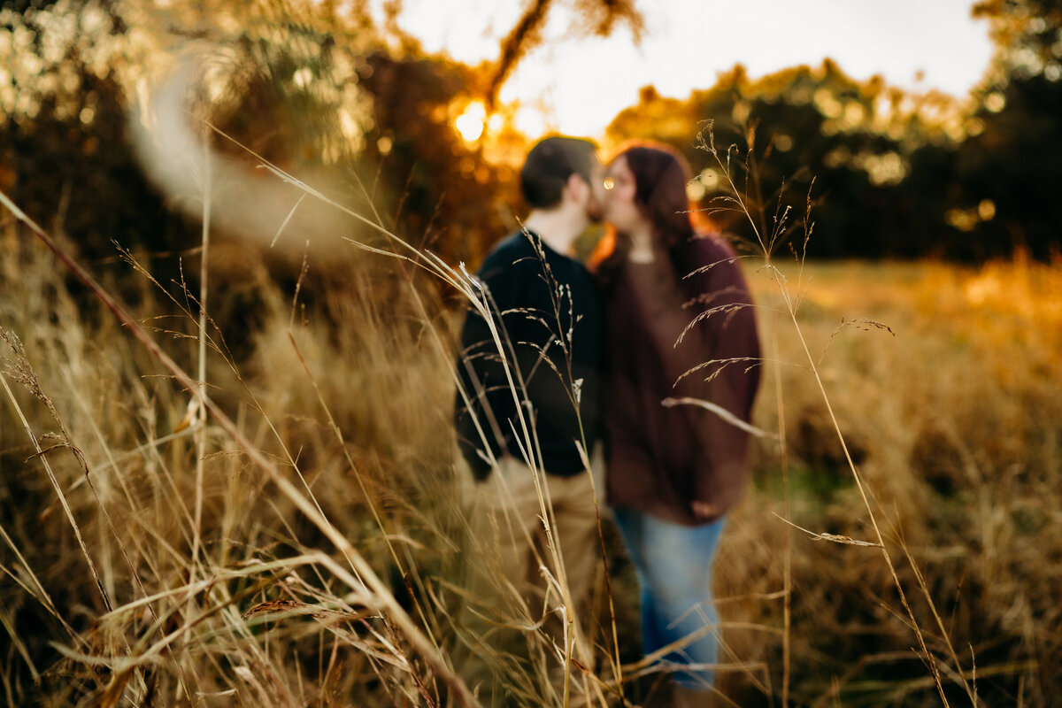 out of focus and candid photo of couple kissing in field in Lafayette, la