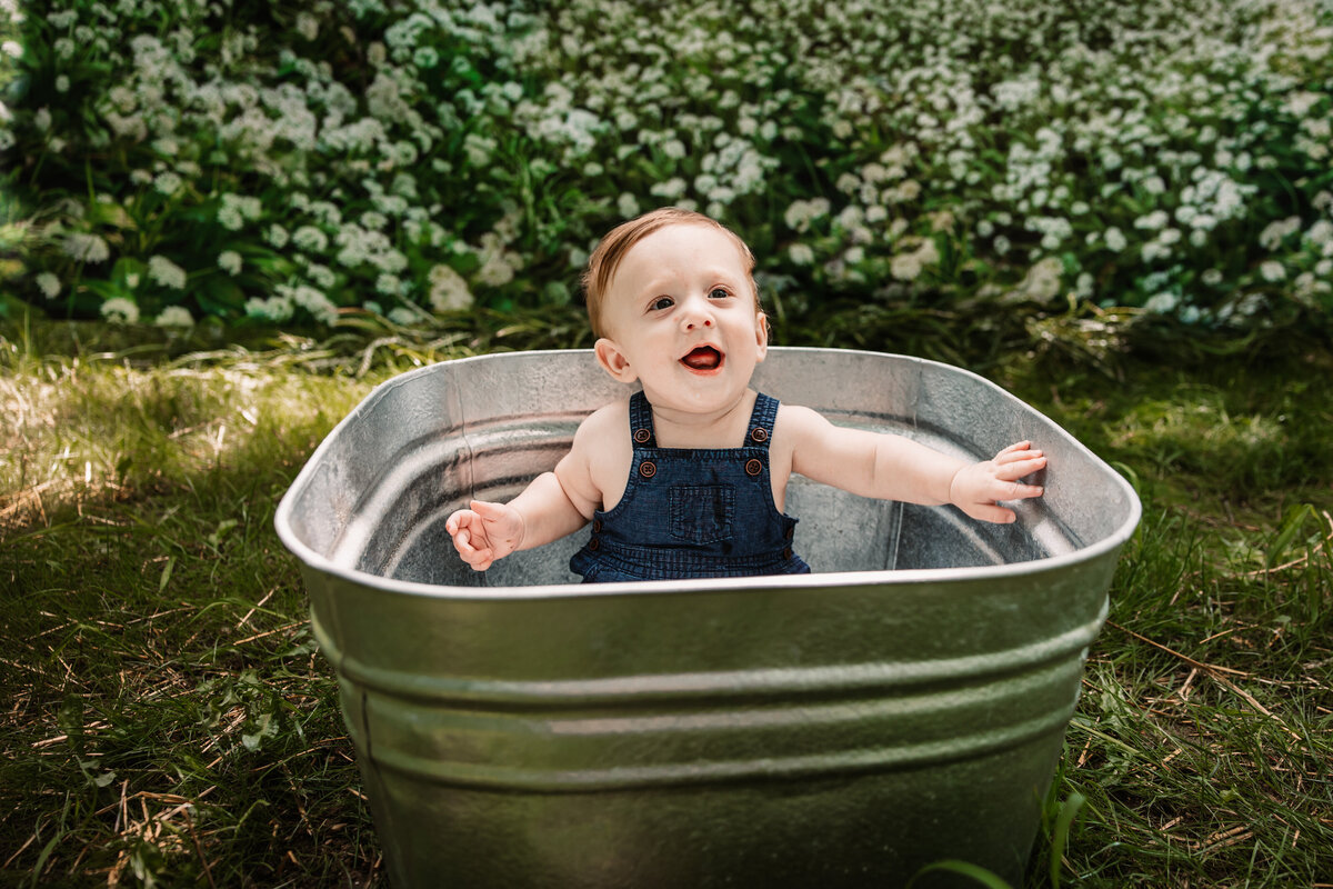 baby sits in galvanized tub in flower field
