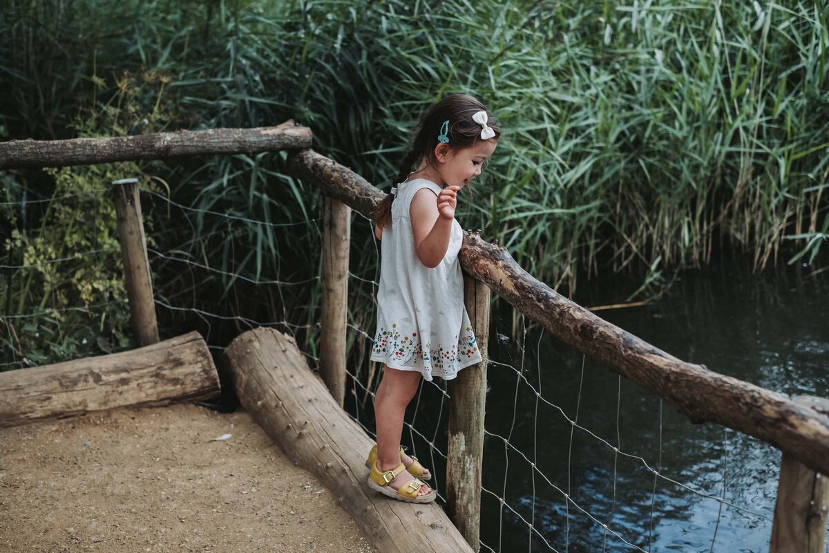 Little girl looks at the ducks in the pond at a park in London