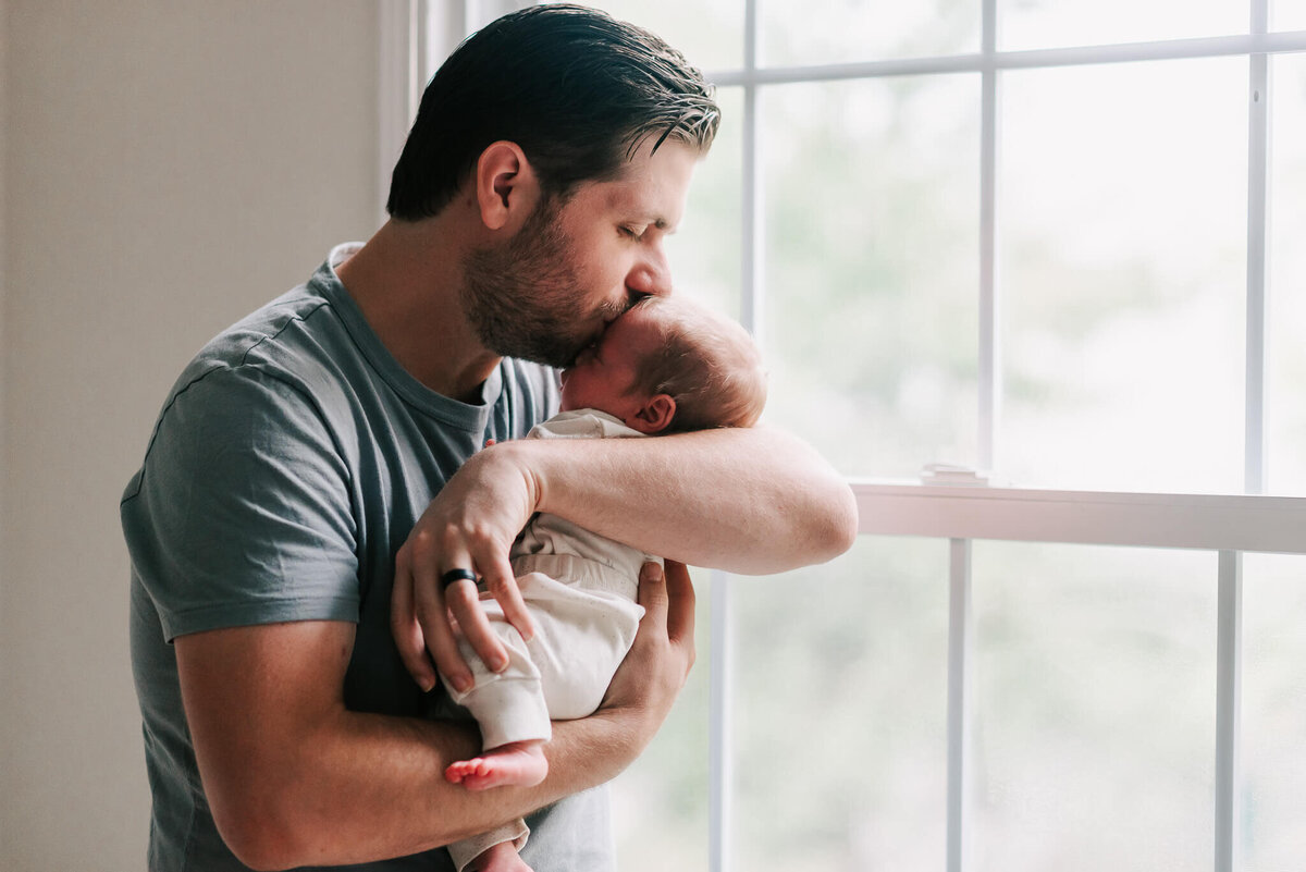 sweet moment between a dad kissing his newborn son