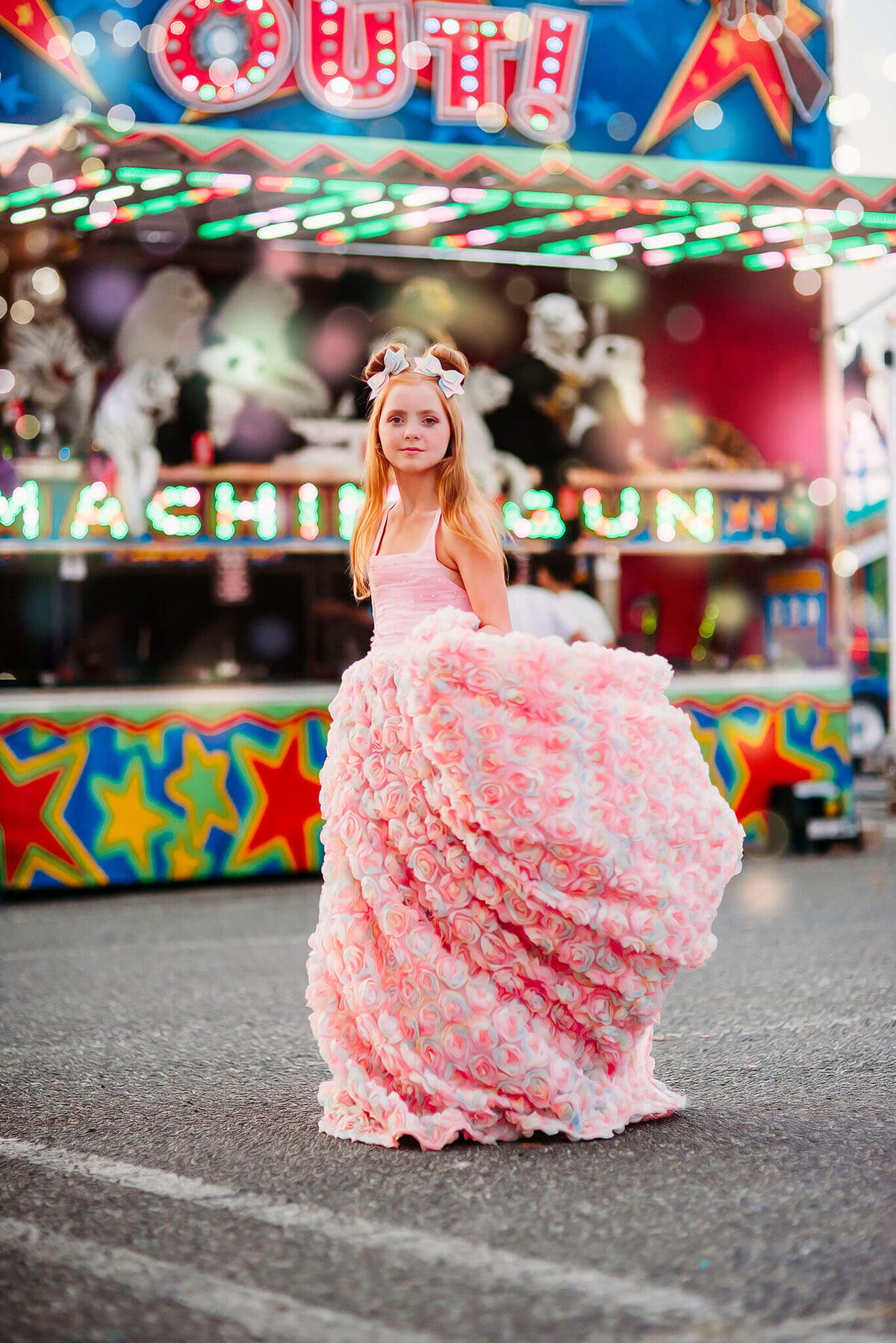 red haired girl in a pink rainbow dress spinning in front of a carnival game near Annapolis Maryland
