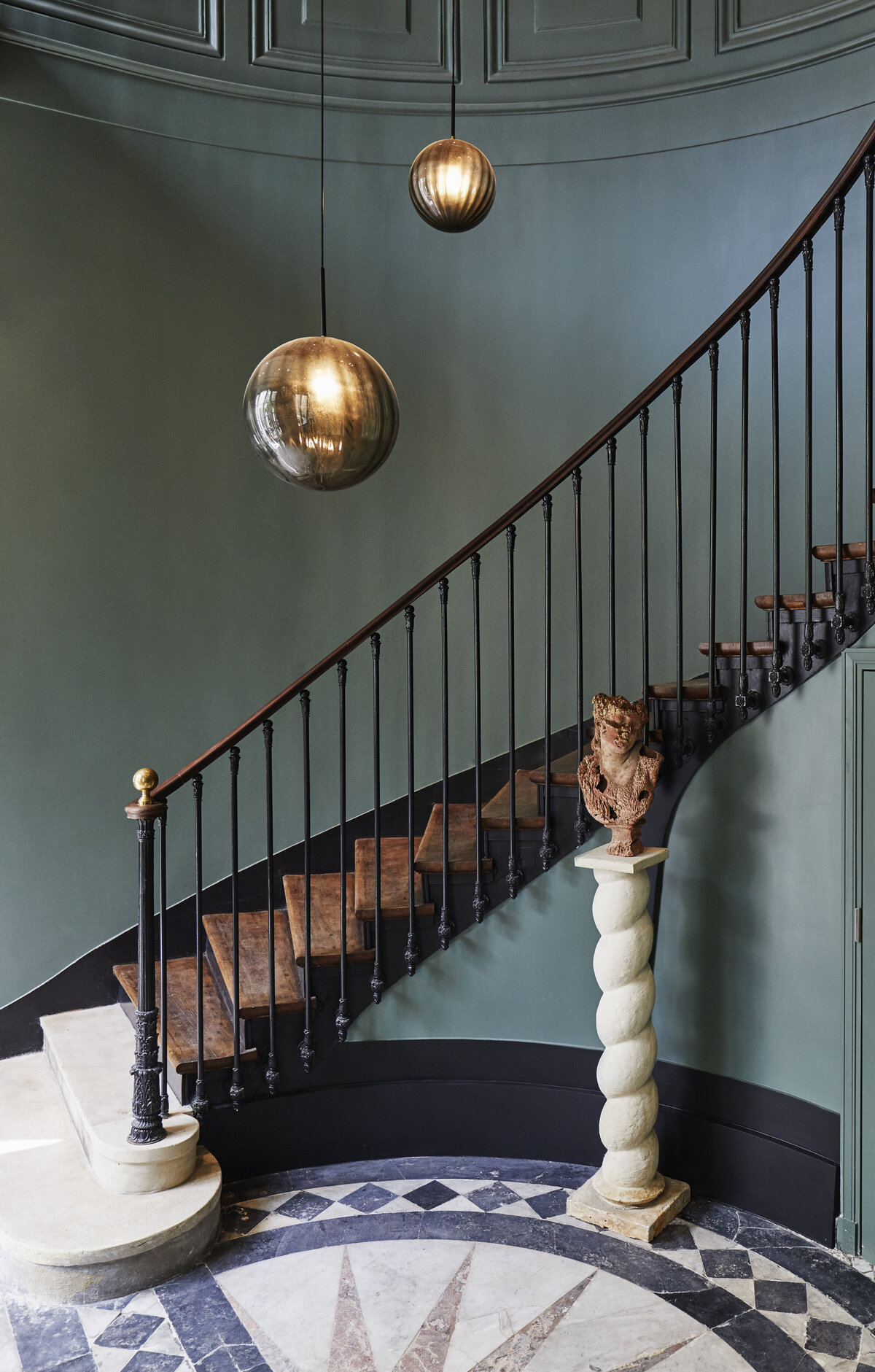 Parisian stairwell with marble floor, staircase with wooden treads, and  metal handrail, teal painted walls