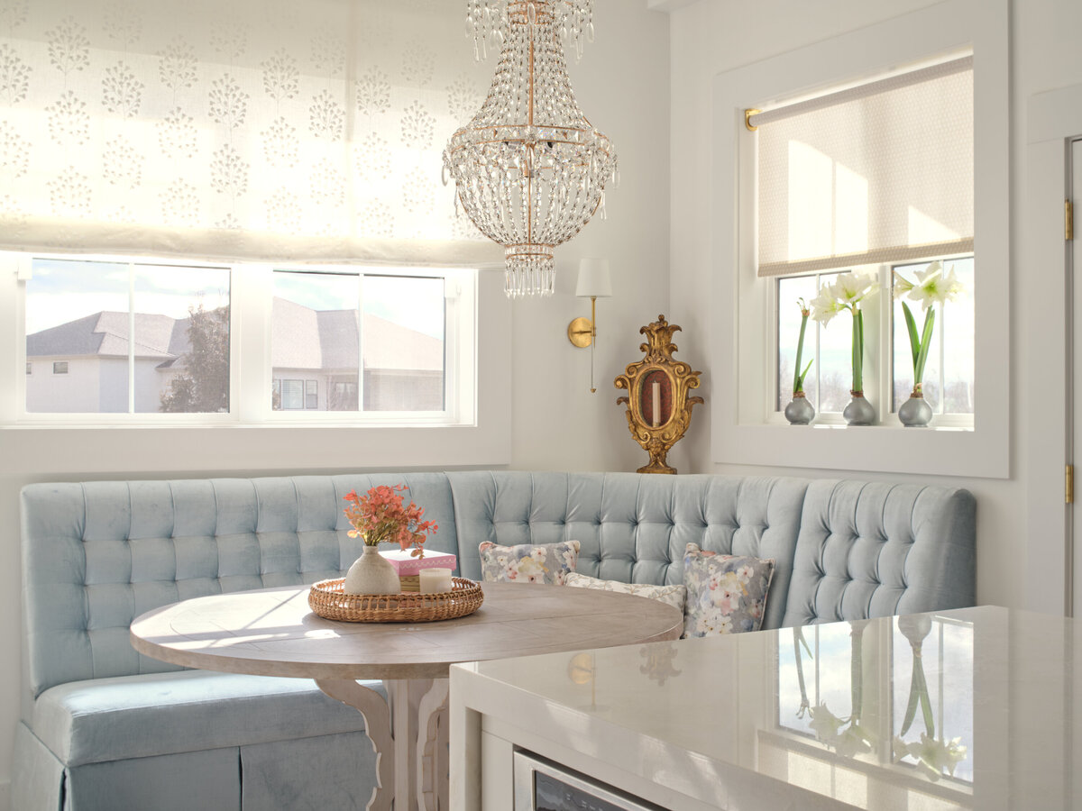 kitchen seating area with  light blue bench seating a round table and  elegant chandelier