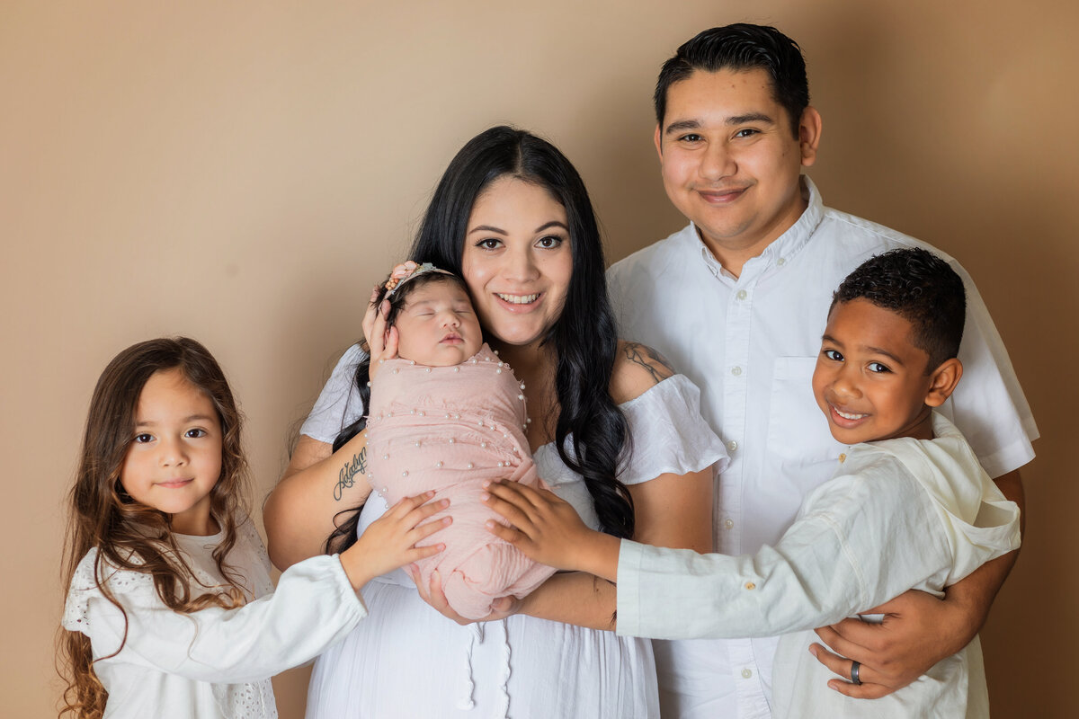 Newborn Photographer, a young family stands with baby sibling