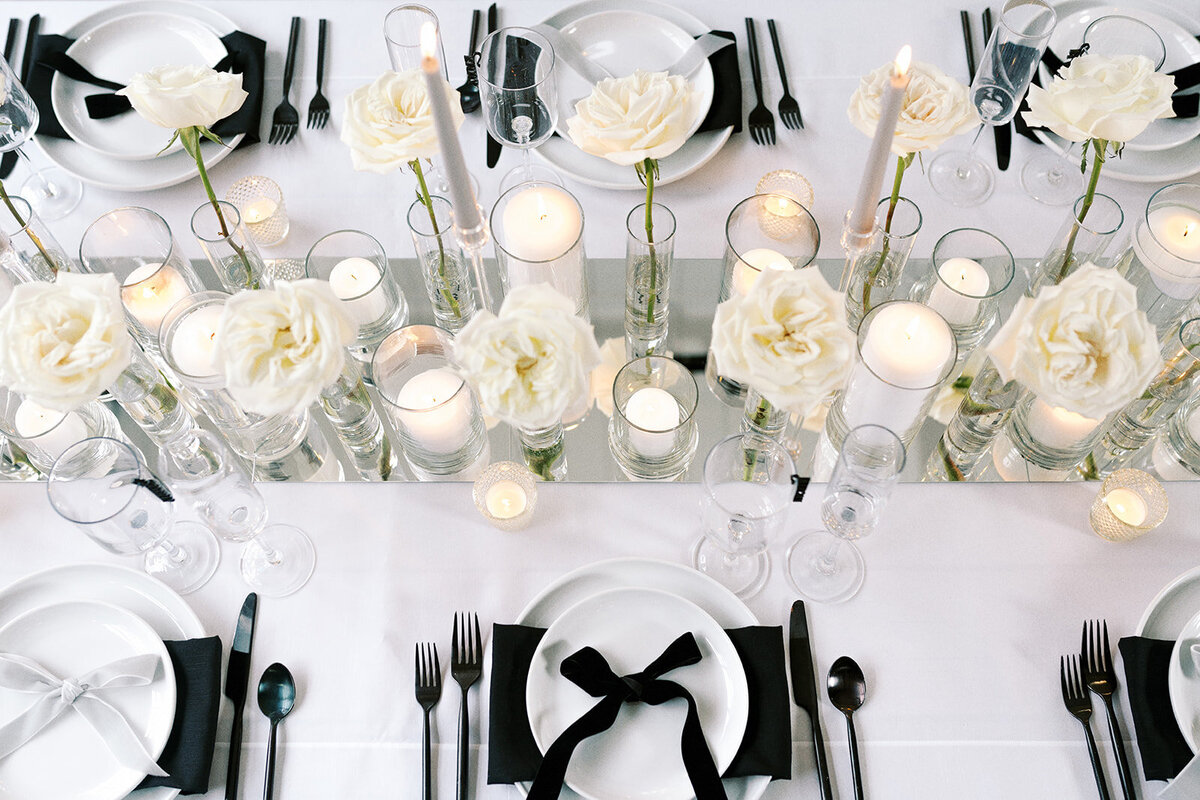 A table with candles, roses, and places settings at a styled wedding shoot.