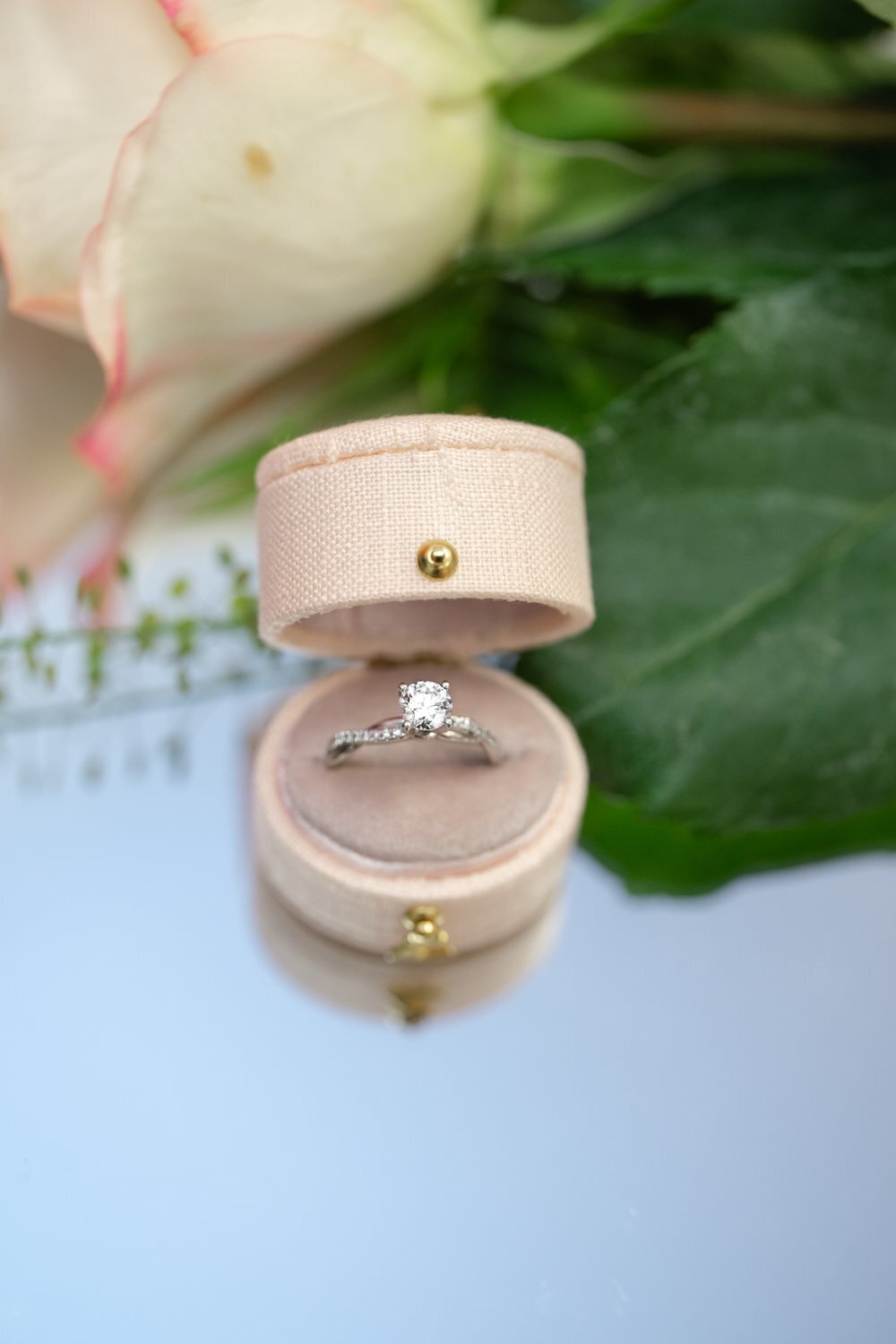 detail image of wedding ring next to rose on mirror