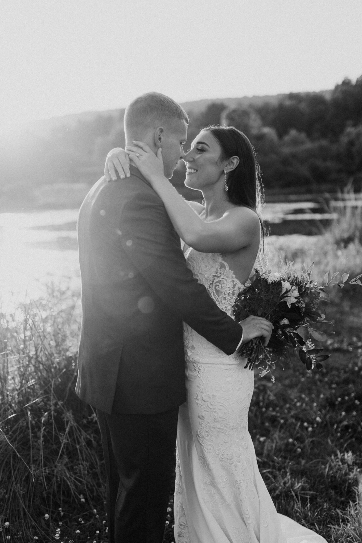black and white photo of a wedding couple with their arms around each other as they are about to kiss