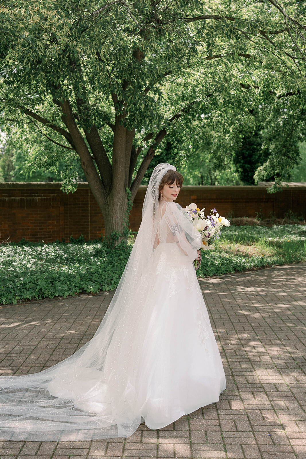 Bride looking over shoulder in natural light outdoor portrait in Michigan
