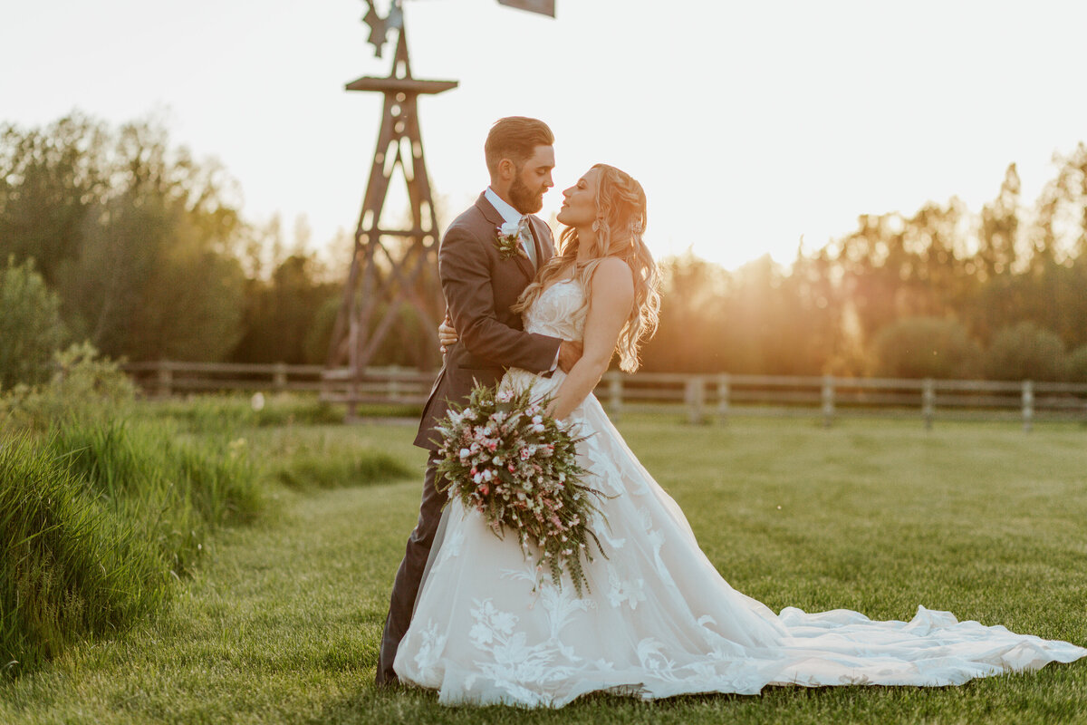 bride and groom posing by windmill
