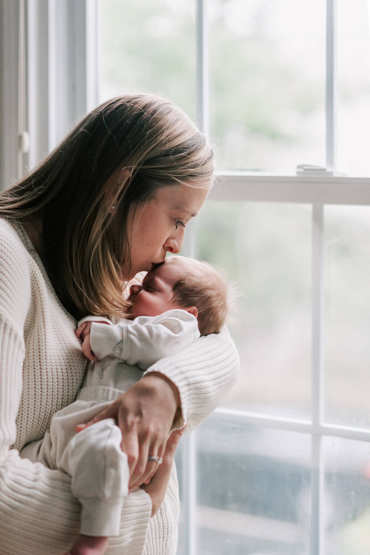 mom kissing her newborn son sweetly on the forehead