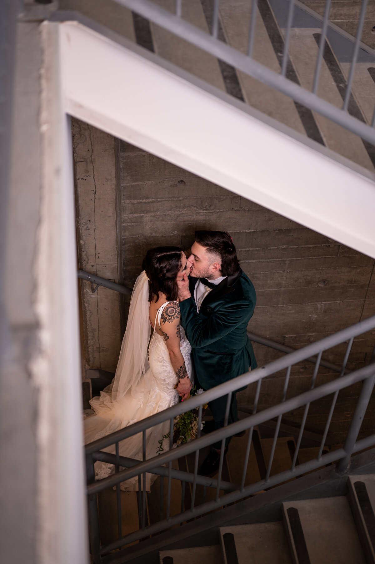 couple kiss under a staircase at the Pendennis Building  wedding venue in Edmonton, Alberta