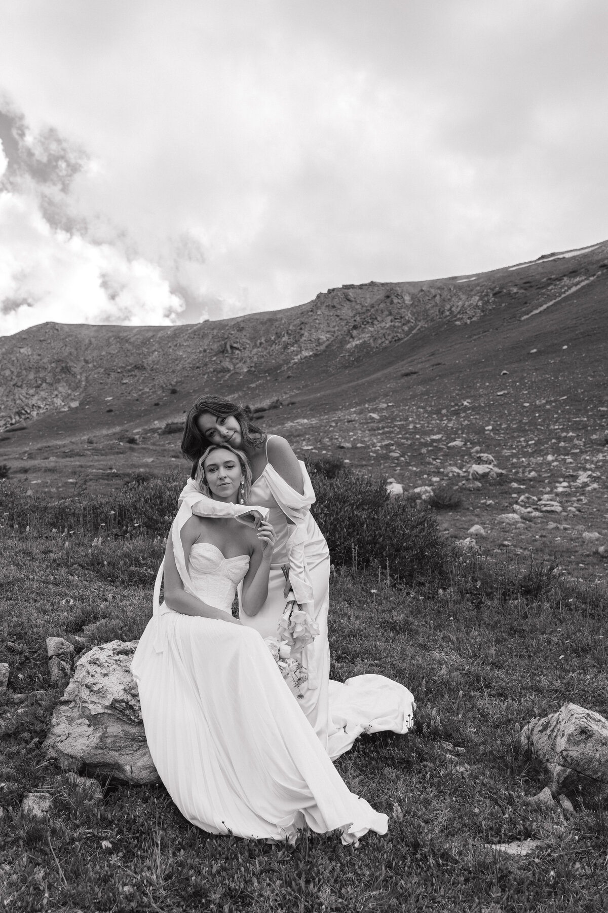 Two brides holding onto each other looking at the camera in the mountains of Breckenridge, Colorado.