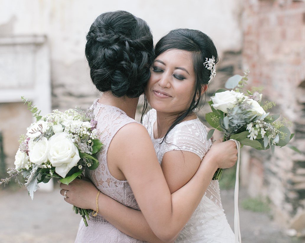 Bride and bridesmaid hugging each other with their bouquets