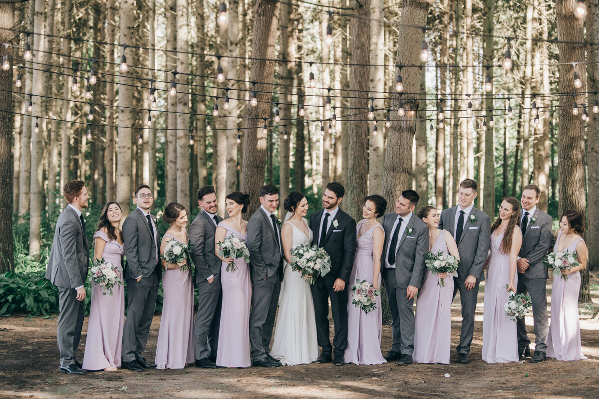 Wedding party wearing. lavender and grey posing for group photos in an enchanted forest