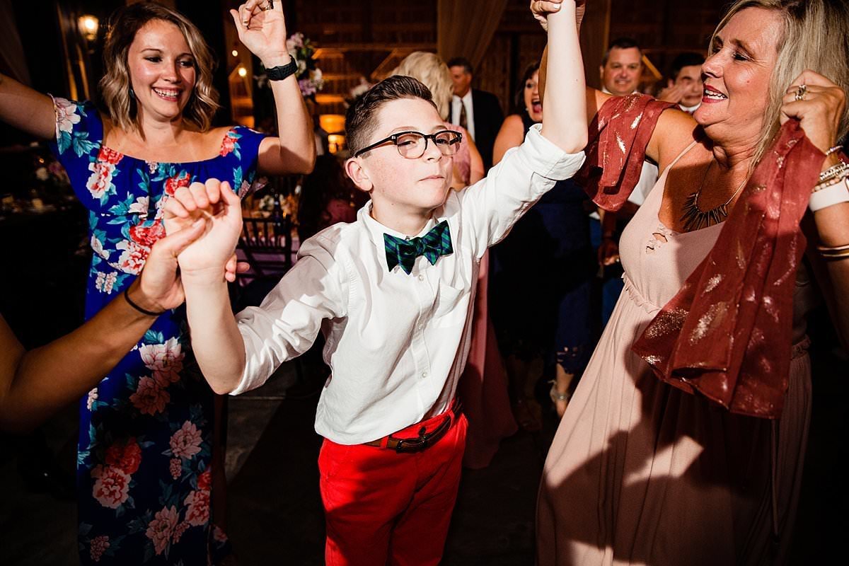 Kid wearing red pants and blue bowtie dancing with arms in air