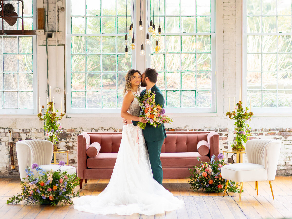 Bride and groom smiling in front of pink velvet couch