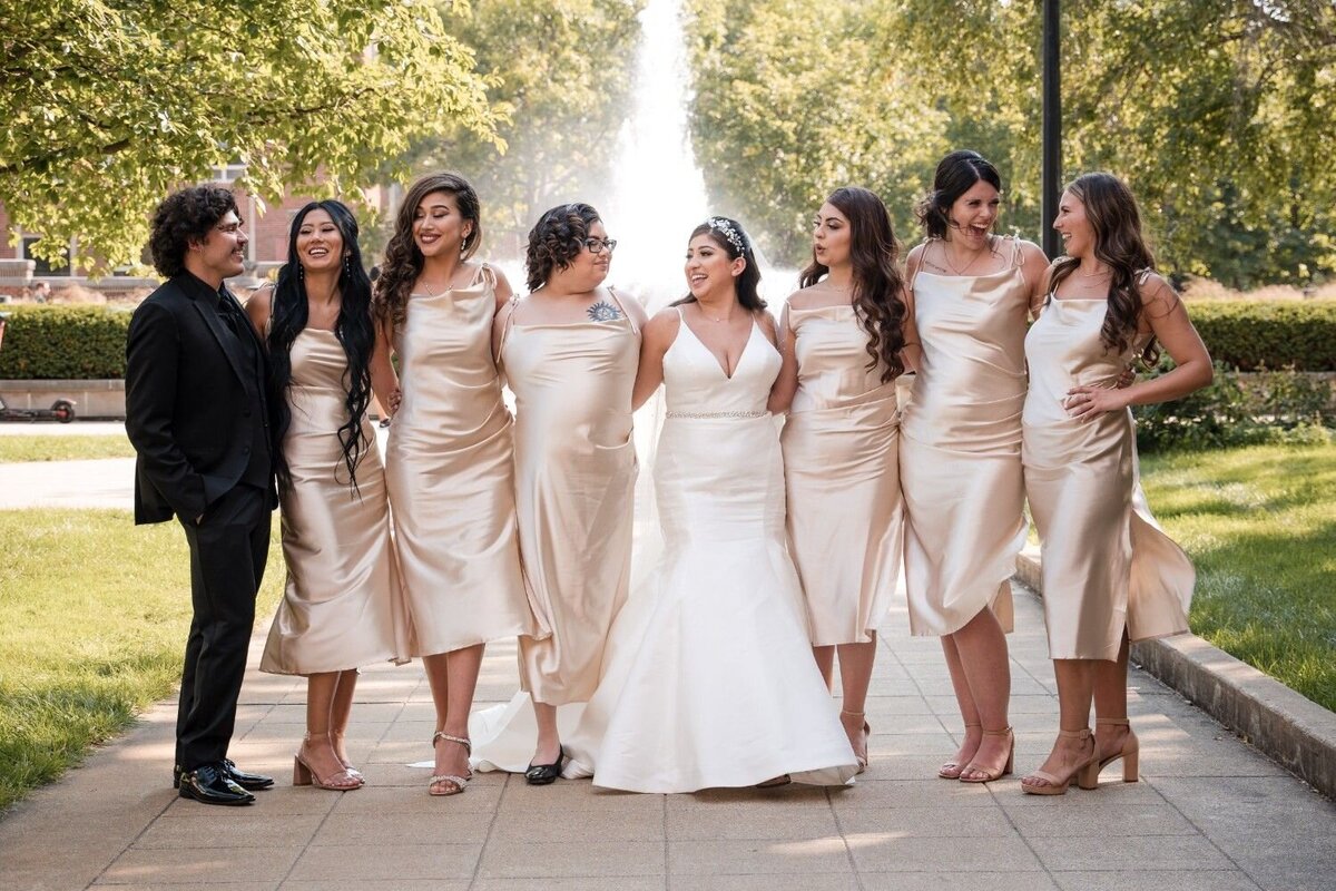 Bride laughing with bridesmaids in champagne satin dresses