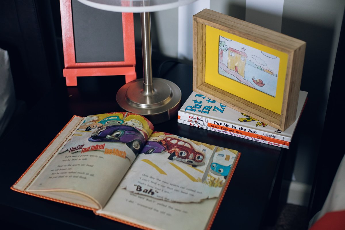 a children's book, picture frame, and lamp on a night stand