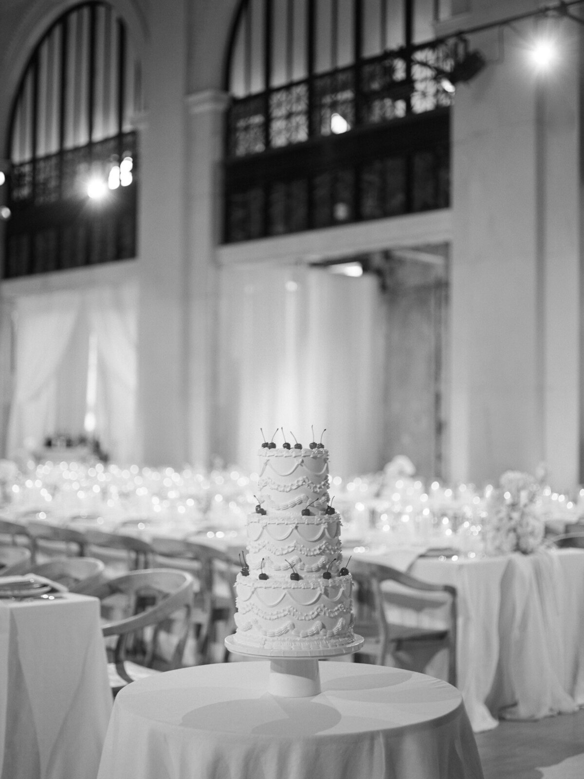A vintage piped wedding cake rests quietly among hundreds of candles for a State Savings Bank wedding in Detroit