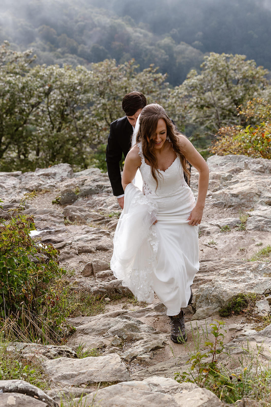 Newlyweds hiking up a rock together