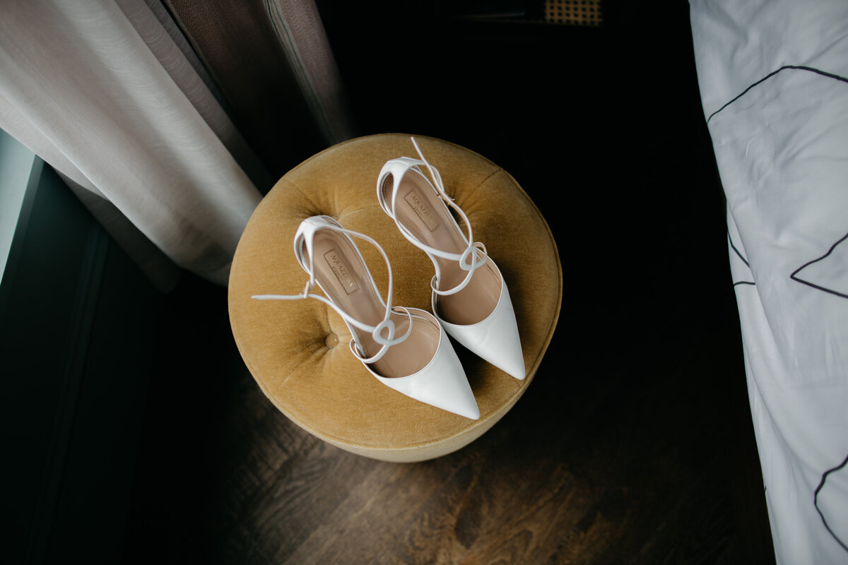 Overhead image of white heels sitting on gold ottoman