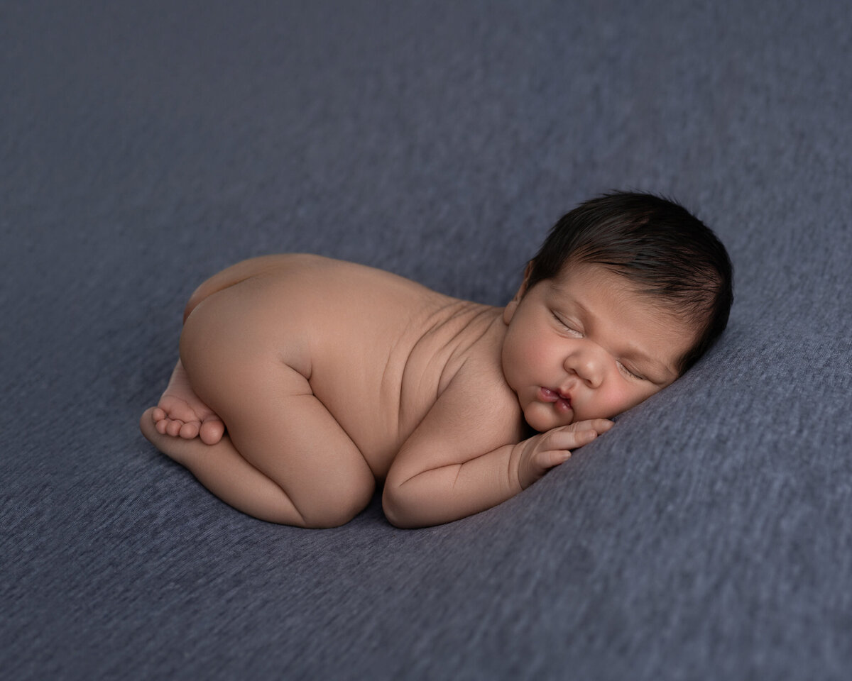Sleeping newborn baby posed nude on a soft blue blanket with gentle natural light | Newborn studio photo near Leander and Buda, Texas