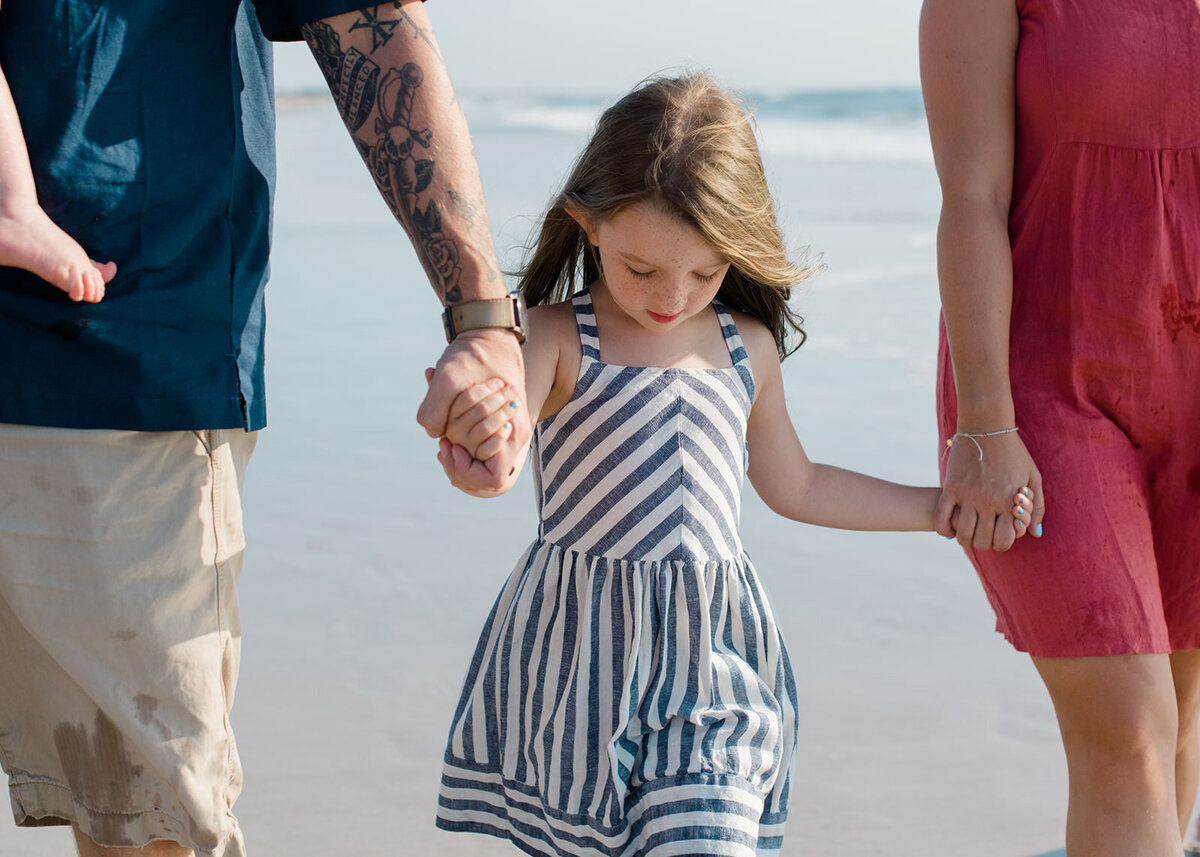 family holding hands while walking on the beach