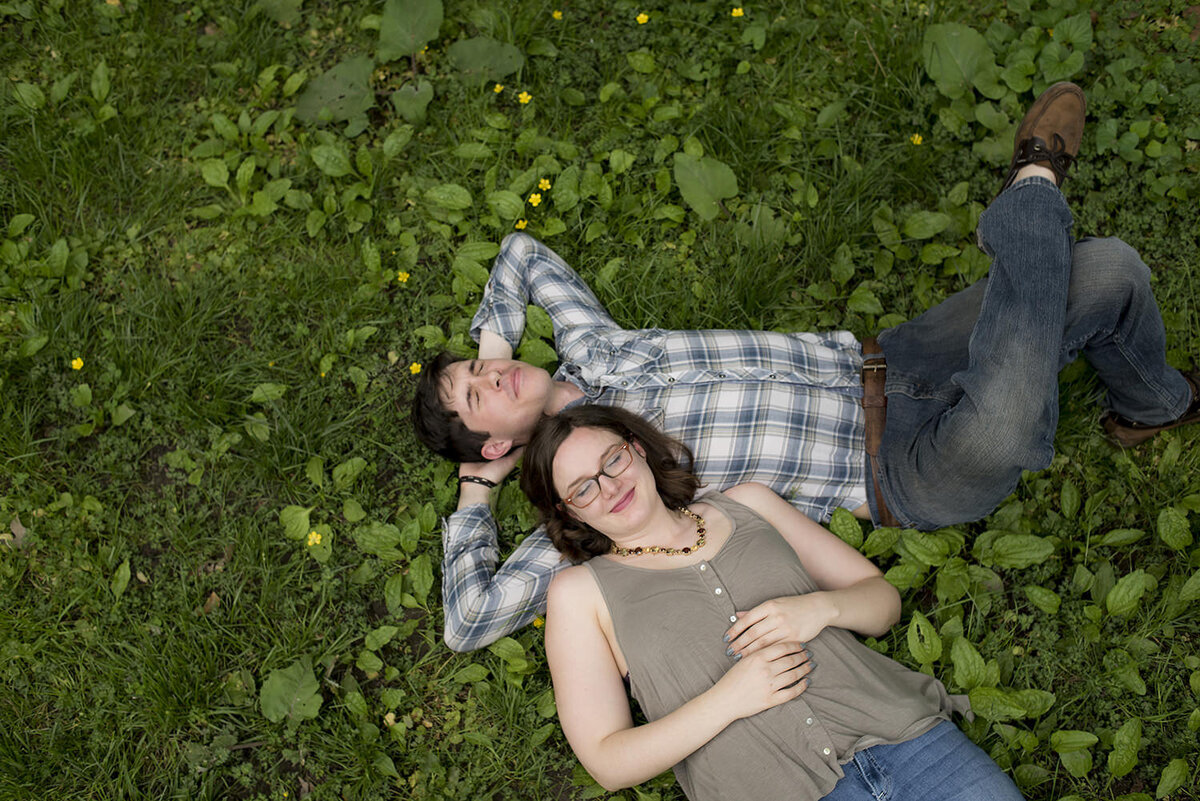 A couple laying on top of each other in the grass 
