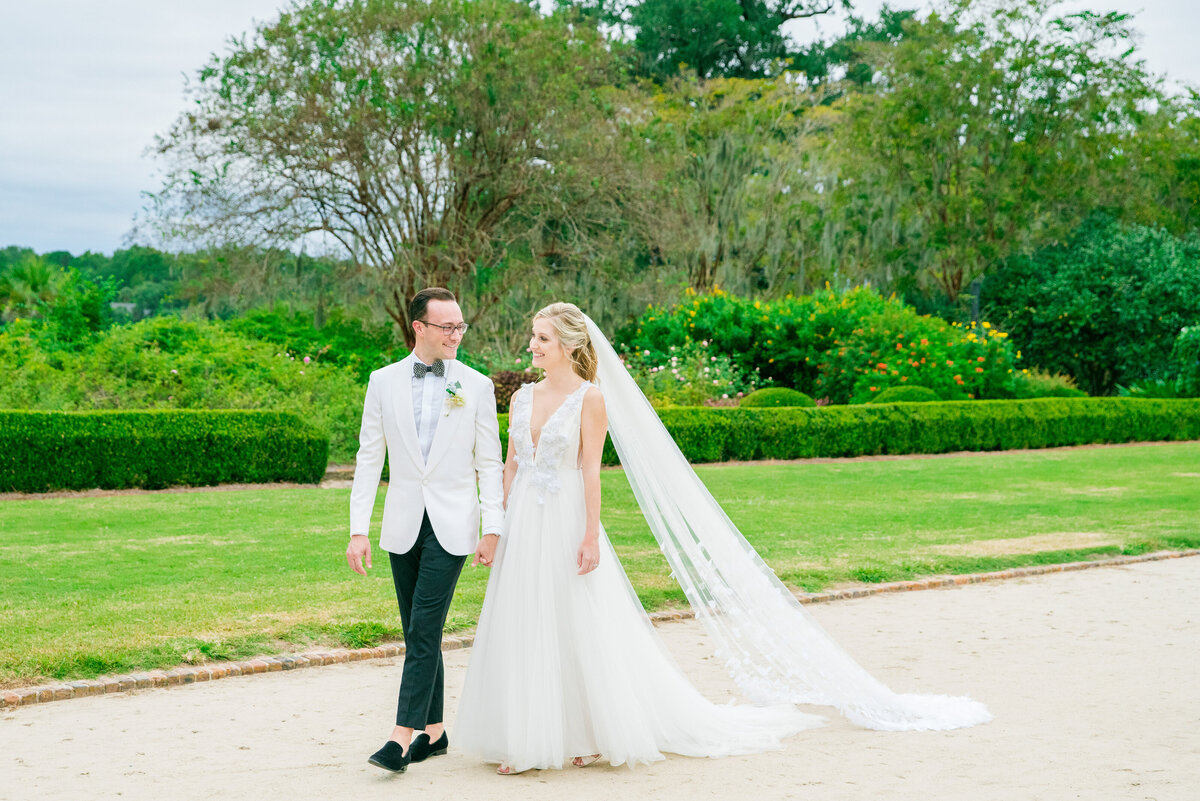 bride and groom walk through avenue of oaks at boone hall sc