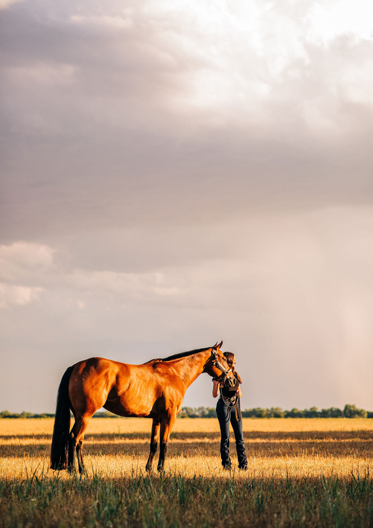 girl standing with horse  with storm in background