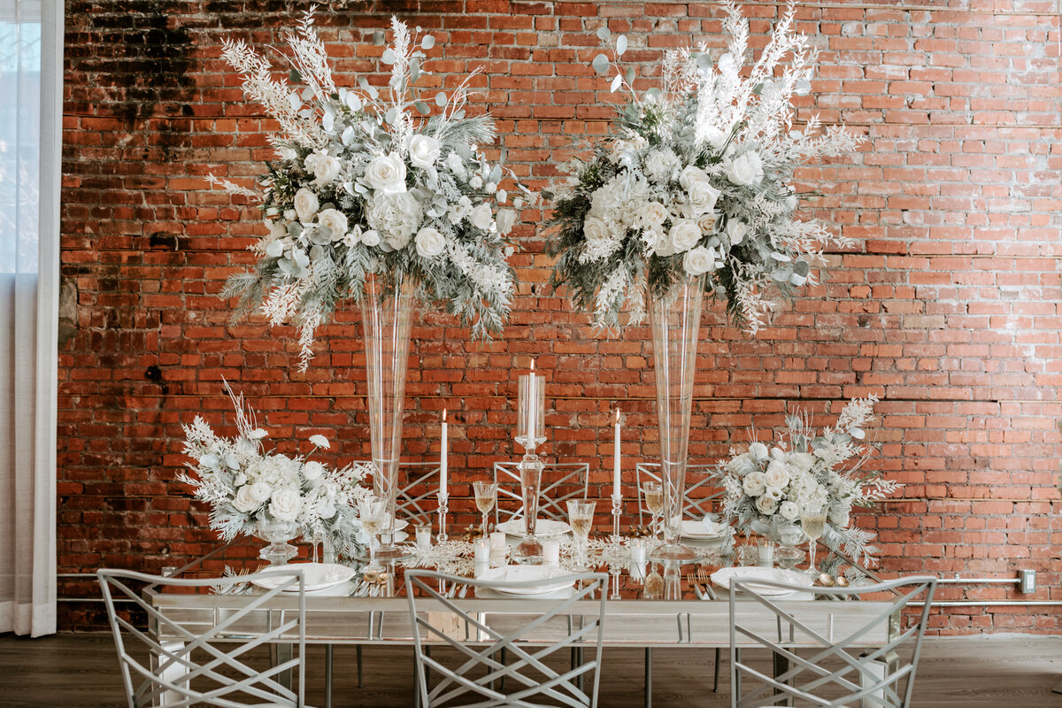 Romantic reception decor with stunning white florals and brick wall backdrop styled by Melissa Dawn Event Designs, a unique and modern wedding planner based in Calgary, Alberta. Featured on the Brontë Bride Vendor Guide.
