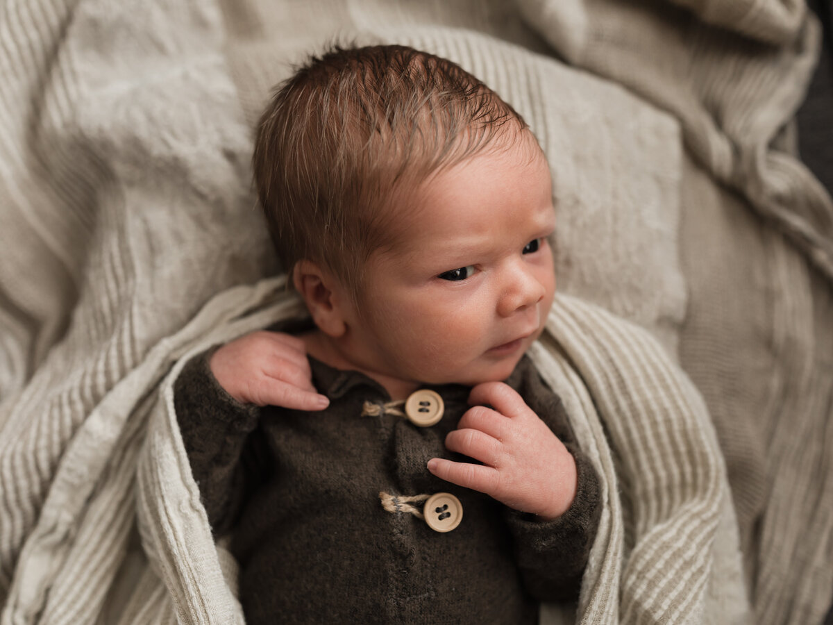newborn baby boy in green outfit for in home lifestyle session