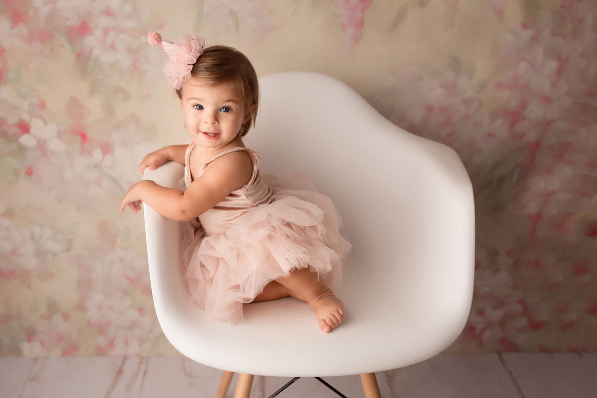 children photo session with a girl sitting in a white chair and smiling