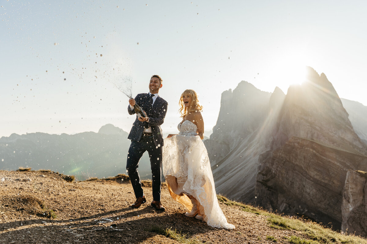 Couple popping champagne at sunrise in the Dolomites