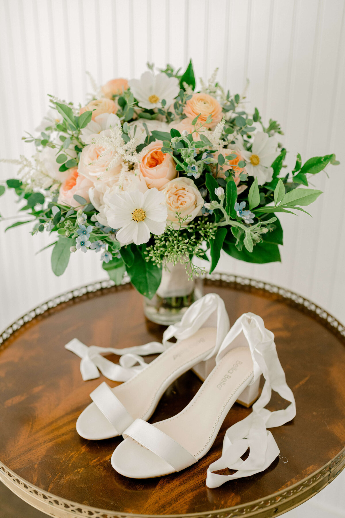 Image taken by DC photographer, Rachael Mattio of a pair of white Bella Belle bridal shoes sitting next to her peach and white bridal bouquet.
