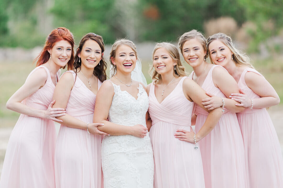 A bride laughs while standing with her 5 bridesmaids