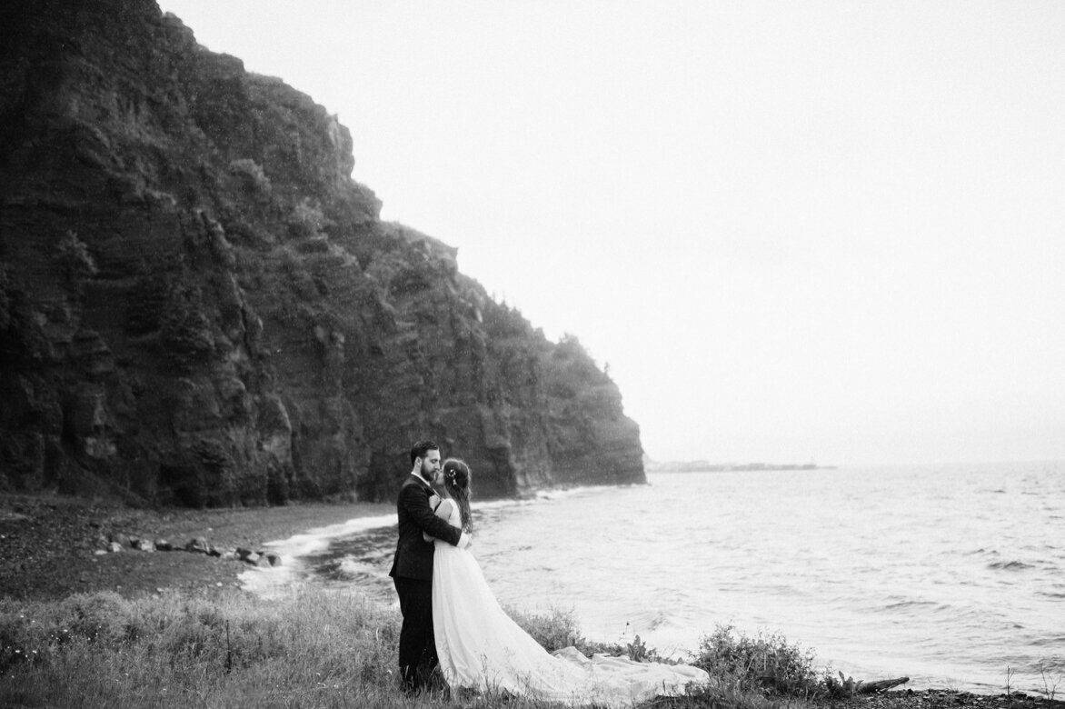 bride and groom laugh while their hair blows in the wind during Newfoundland elopement on the coast