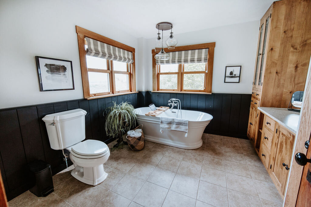 second story bathroom with black wainscotting and freestanding bath soaker tub in the modern farmhouse at Willowbrook wedding venue