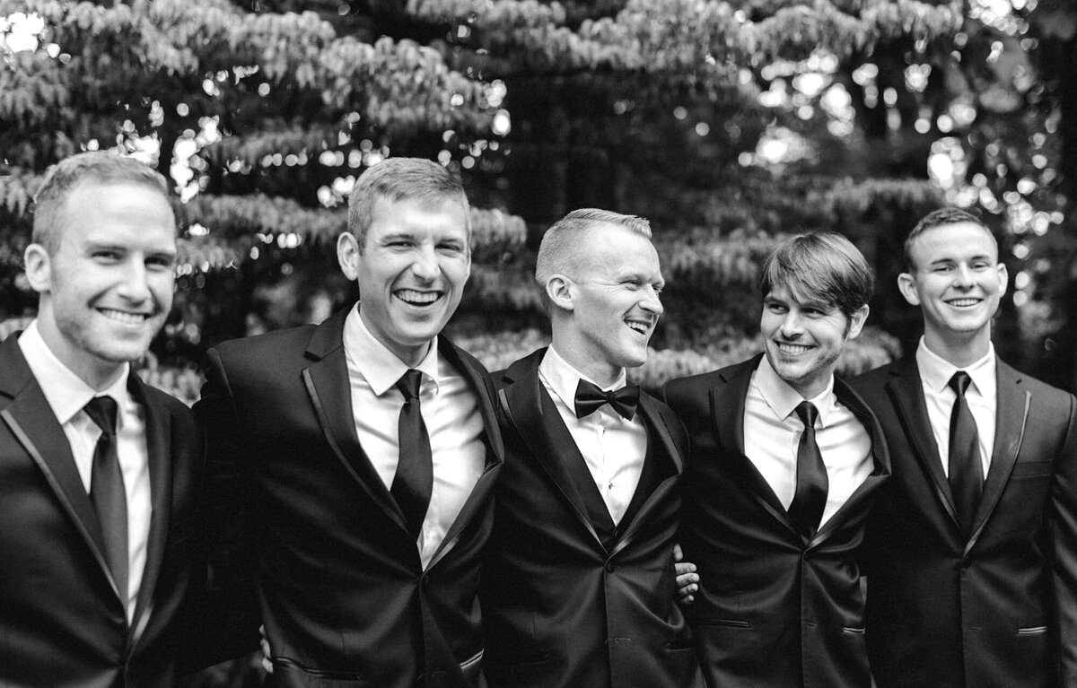 Groom and groomsmen with arms around each other laughing at Charlottesville downtown wedding