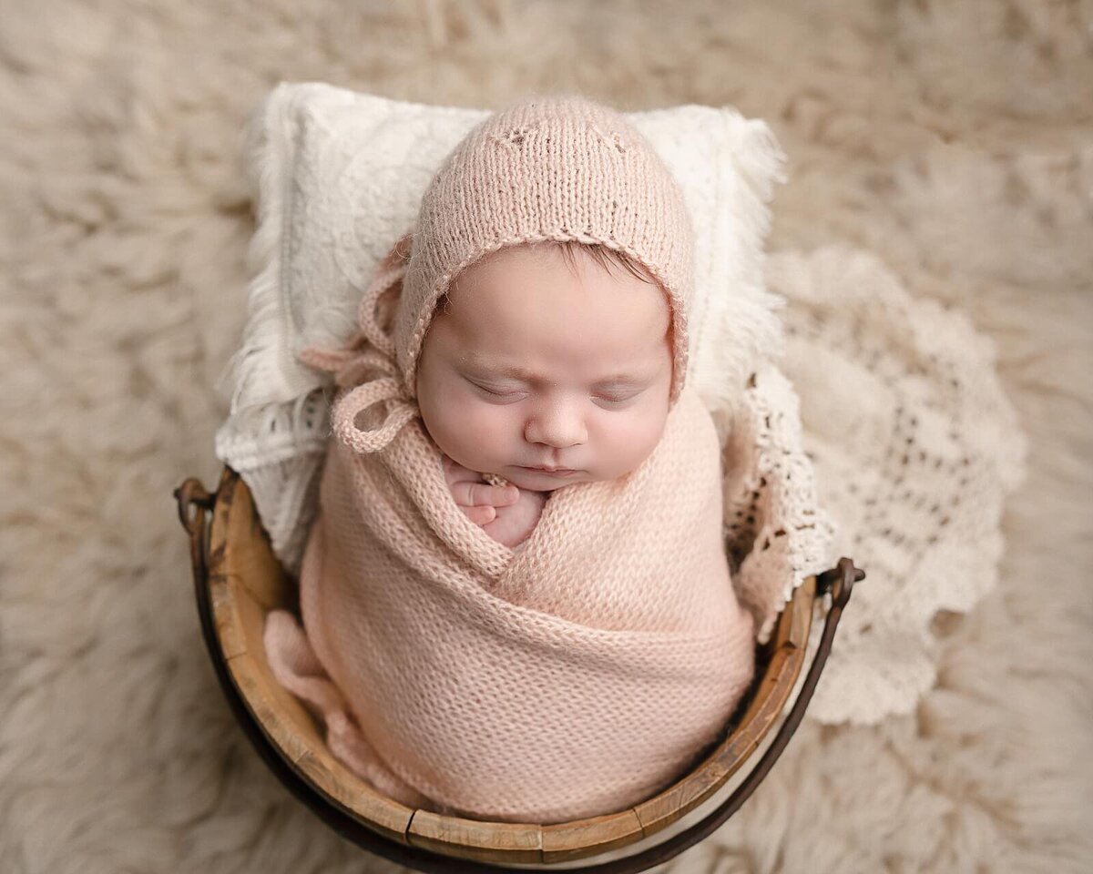 baby girl in peach blanket in bucket