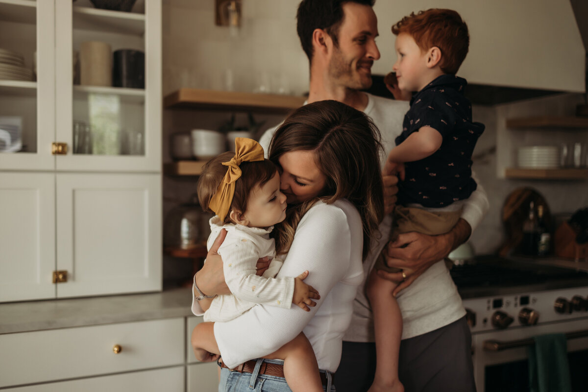 family of four cuddle in kitchen
