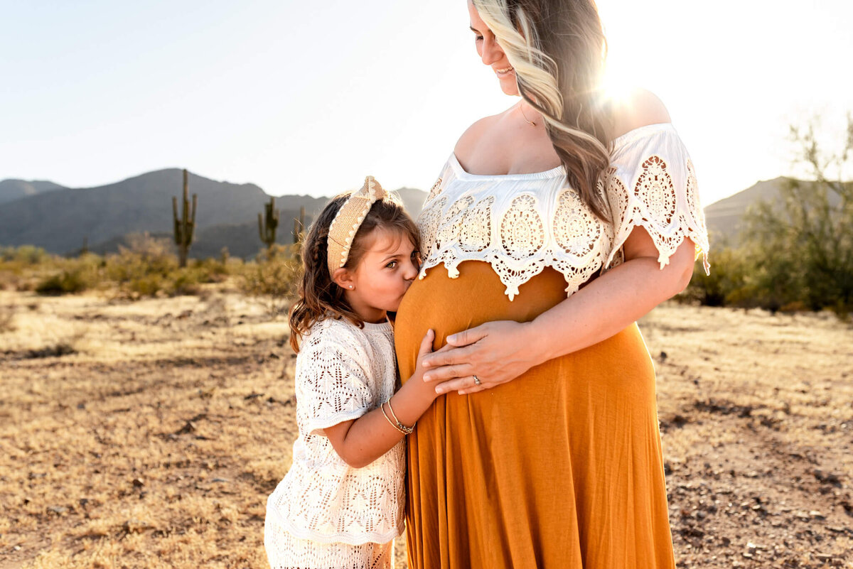 Daughter kissing mom's pregnant belly. Taken by Cactus & Pine Photography