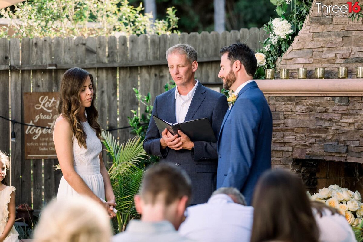 Bride and Groom close their eyes as the officiant leads with a prayer